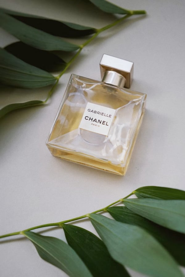 A perfume bottle in a table with a leaf near